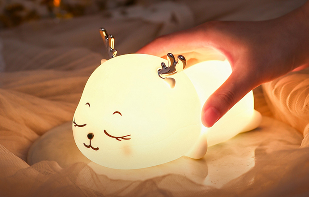 Night Light for Children: SuperFire L07 Little Elk emitting yellow light. A hand is visible touching the device to adjust the light color.